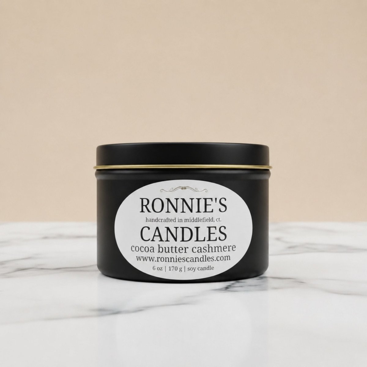 Black candle tin with a white label on a marble surface